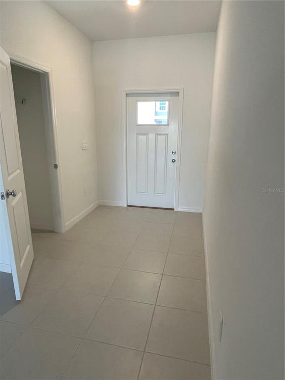 An entryway features light-colored floor tiles, white walls, and a white front door with glass — 36217 RISA MICHELE STREET, ZEPHYRHILLS, FL