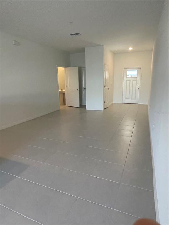 An interior view of a room with light-colored tile flooring, white walls, and several doors — 36217 RISA MICHELE STREET, ZEPHYRHILLS, FL