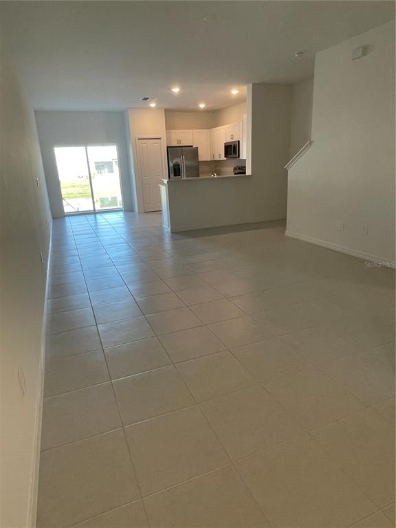 An open-concept living area features light-colored tile flooring and a kitchen with white cabinetry — 36217 RISA MICHELE STREET, ZEPHYRHILLS, FL