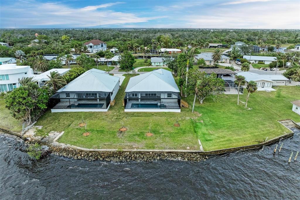 An aerial view shows two waterfront houses with screened-in pools and a shared grassy lawn — 112 NORTHSHORE TERRACE, PORT CHARLOTTE, FL