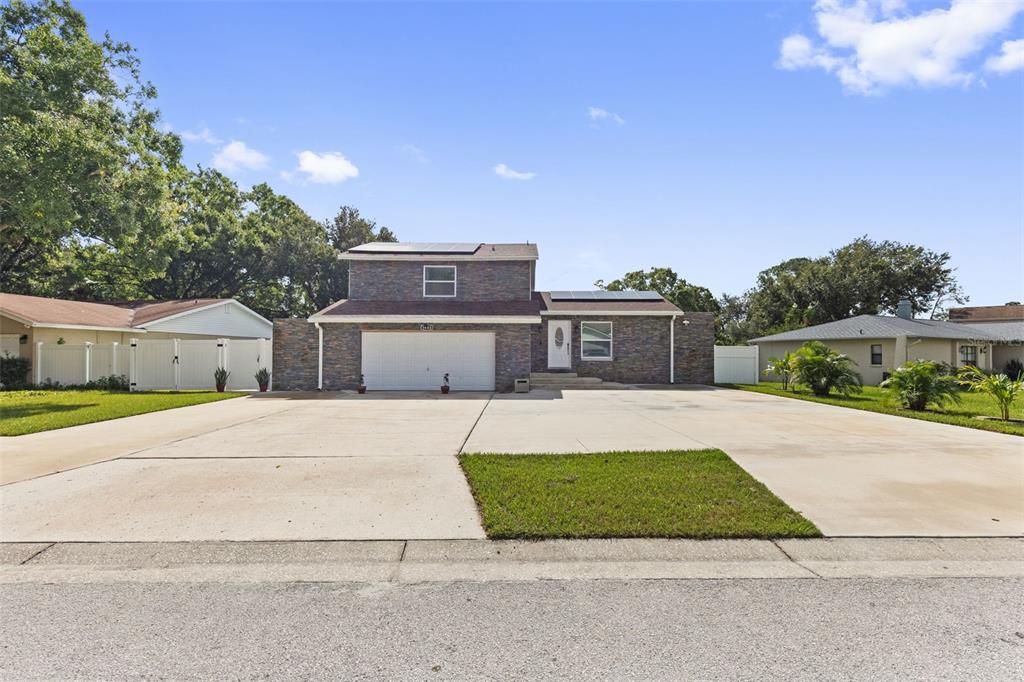 A two-story house with a stone facade, a two-car garage, and solar panels on the roof — 5408 PENTAIL CIRCLE, TAMPA, FL