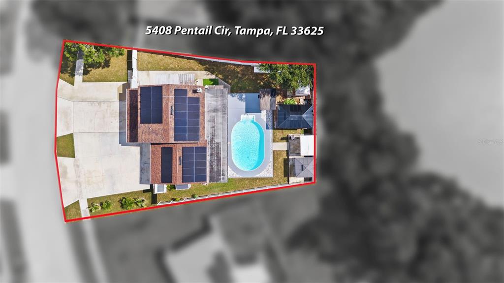 An aerial view shows a house with solar panels and a swimming pool on a lot — 5408 PENTAIL CIRCLE, TAMPA, FL