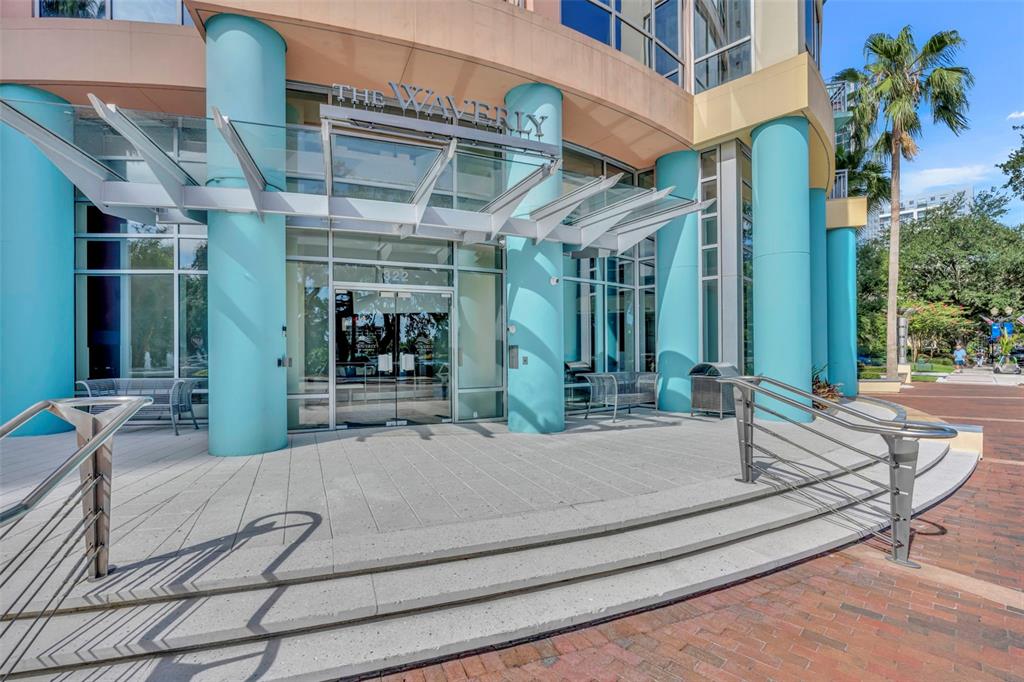The exterior entrance of a modern building features teal columns and a glass canopy — 322 E CENTRAL BOULEVARD UNIT 1913, ORLANDO, FL