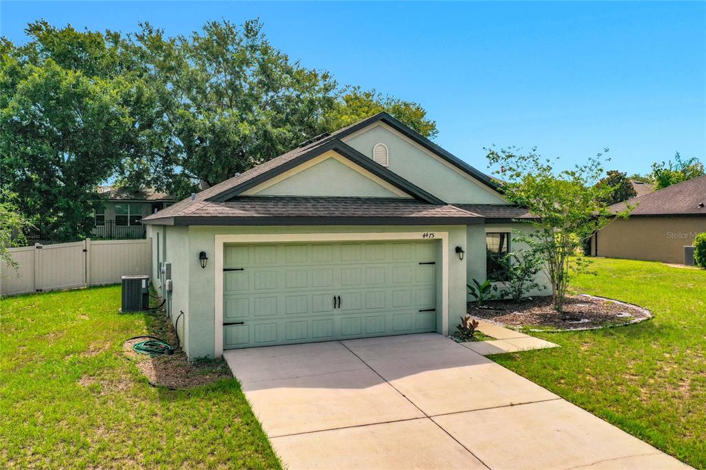 A single-story house with a light green stucco exterior and a two-car garage — 4475 CAICOS DRIVE, TAVARES, FL
