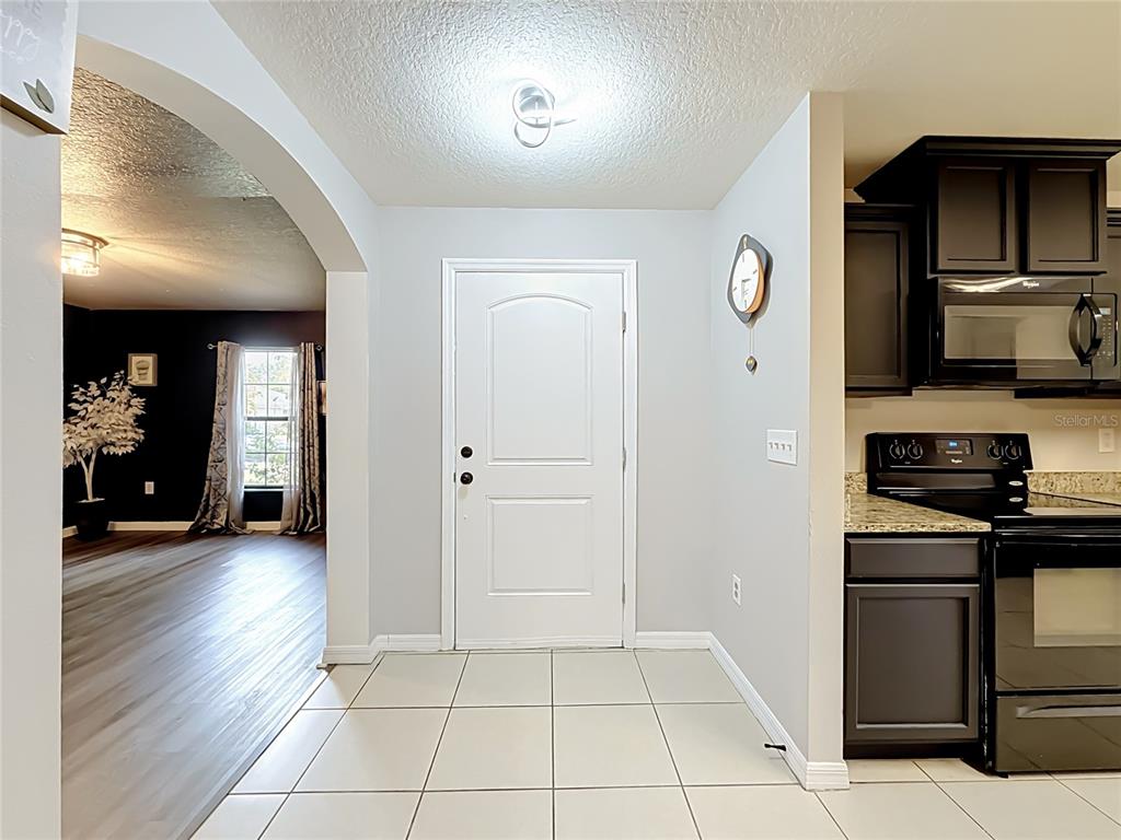 A tiled entryway leads to a kitchen with dark cabinets and an adjacent living area — 4475 CAICOS DRIVE, TAVARES, FL