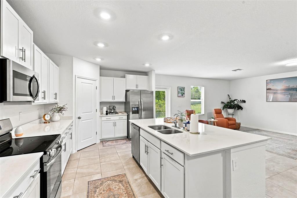 A modern kitchen features white cabinets, stainless steel appliances, and a large central island — 13969 LILAC SKY TERRACE, BRADENTON, FL