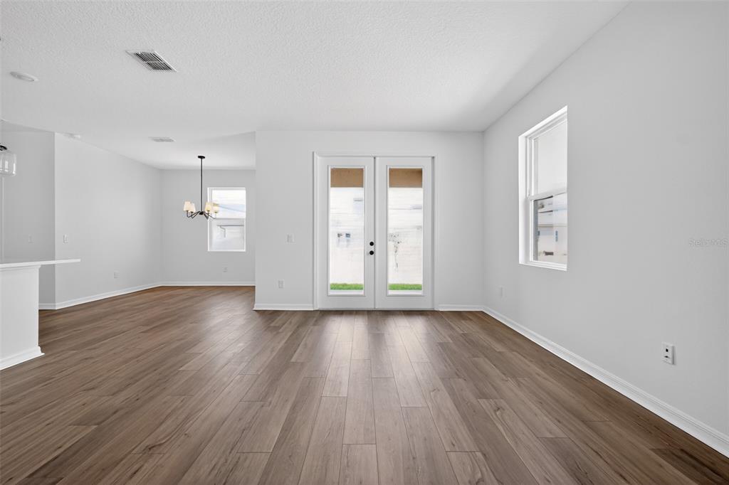 A bright living area features wood-look flooring, white walls, and glass French doors — 30130 EMERALD FOREST DRIVE, MOUNT DORA, FL