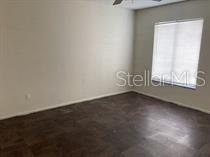 An empty bedroom features dark tile flooring, light-colored walls, and a window with white blinds — 11151 IRON BRIDGE ROAD, ORLANDO, FL