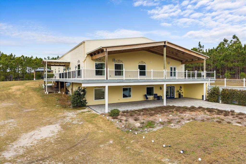 A two-story yellow house features a large elevated deck and a covered ground-level patio — 455 BRIAR PATCH LANE, GENEVA, FL