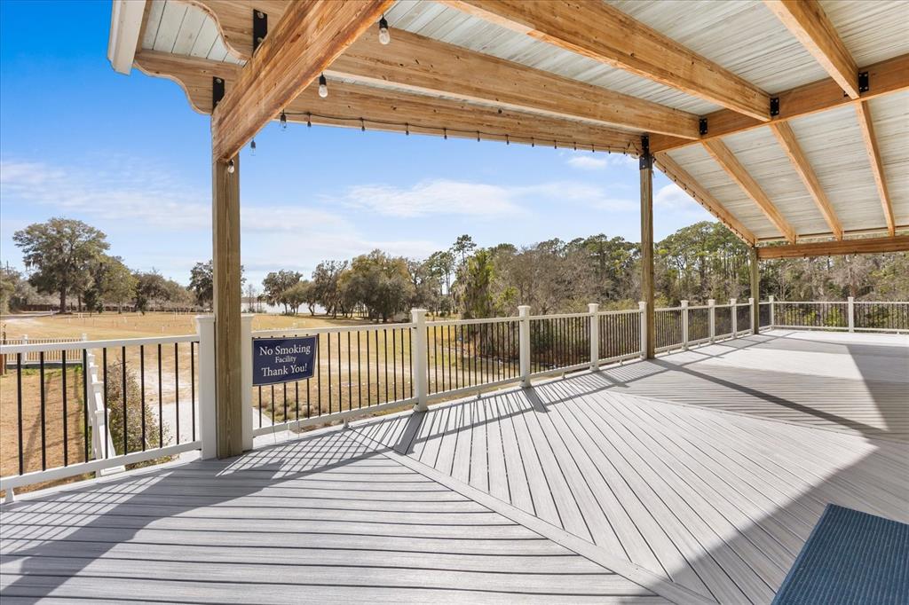 A covered wooden deck features a railing and a view of trees and water — 455 BRIAR PATCH LANE, GENEVA, FL