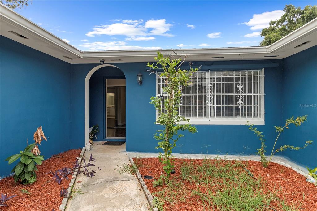 An open living area features dark hardwood flooring, white walls, and a central television stand — 1700 NEEDLEWOOD LANE, ORLANDO, FL