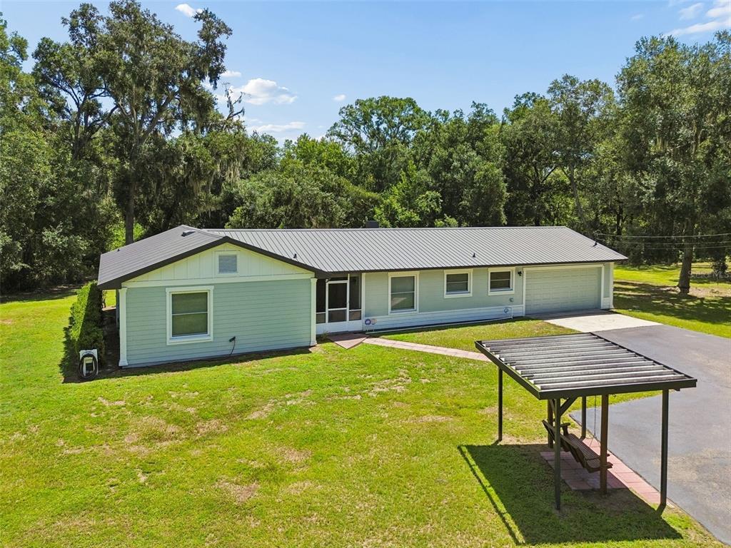 An exterior view of a single-story house with light green siding and a metal roof — 2321 WOOTEN ROAD, DOVER, FL