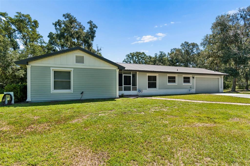 A single-story house with light green siding, a metal roof, and an attached garage — 2321 WOOTEN ROAD, DOVER, FL