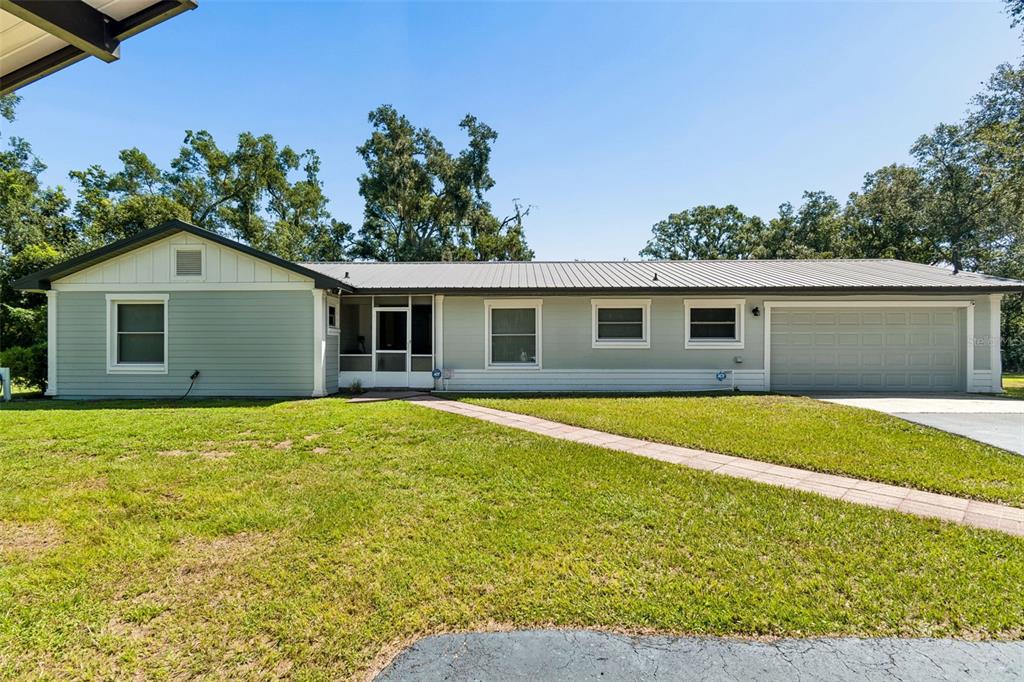 A single-story house with light green siding, a metal roof, and an attached garage — 2321 WOOTEN ROAD, DOVER, FL