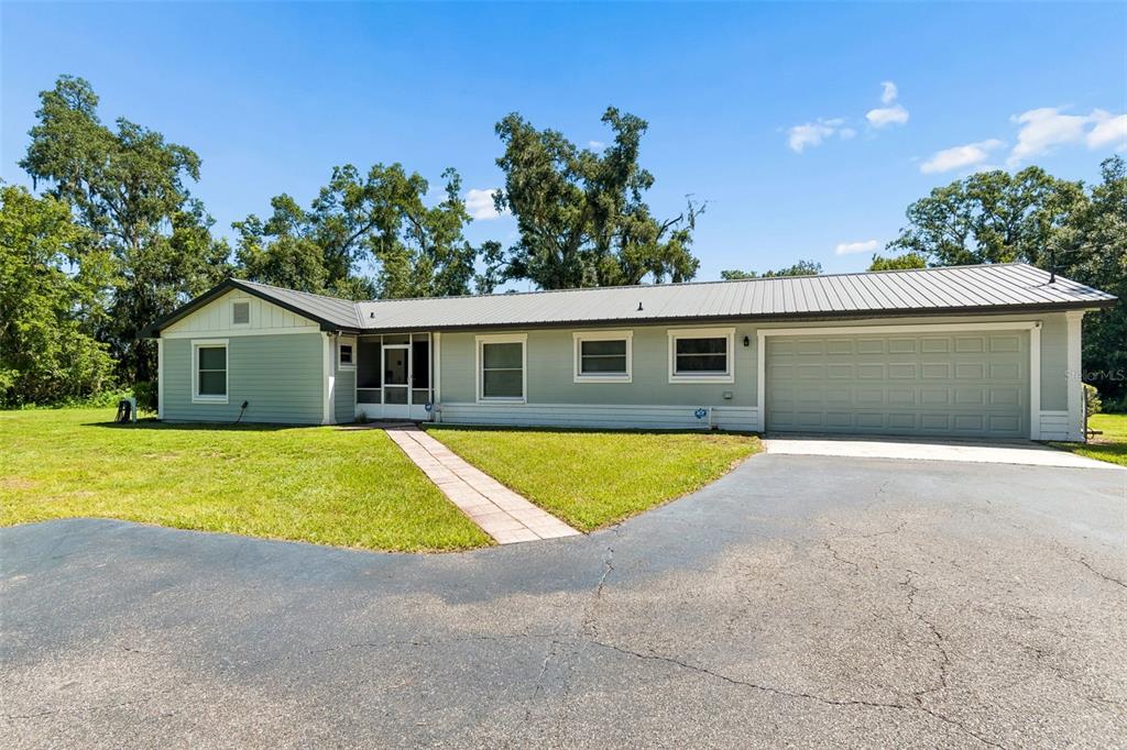 A wooden porch swing hangs under a covered patio area in front of a house — 2321 WOOTEN ROAD, DOVER, FL