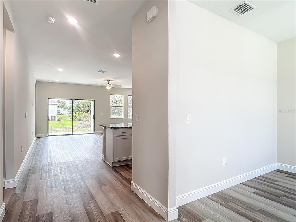 An interior view shows a kitchen island, wood-look flooring, and a sliding glass door — 3008 BREWSTER ROAD, NORTH PORT, FL