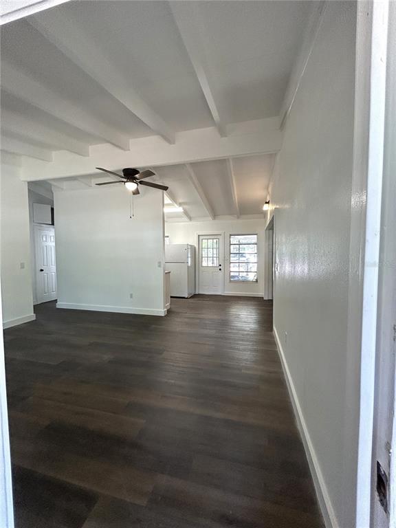 An open-concept living area features white walls, exposed ceiling beams, and dark wood-look flooring — 34798 EVERGREEN WAY, DADE CITY, FL