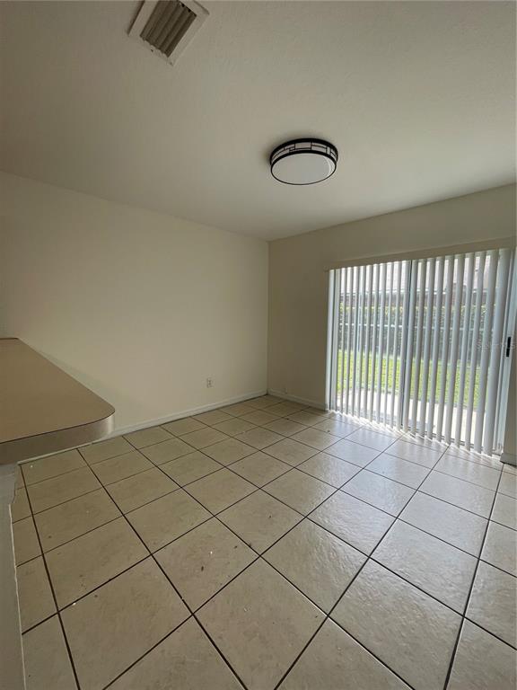 A dining area features beige tile flooring, a flush-mount light fixture, and sliding glass doors — 342 CERVANTES DRIVE, KISSIMMEE, FL