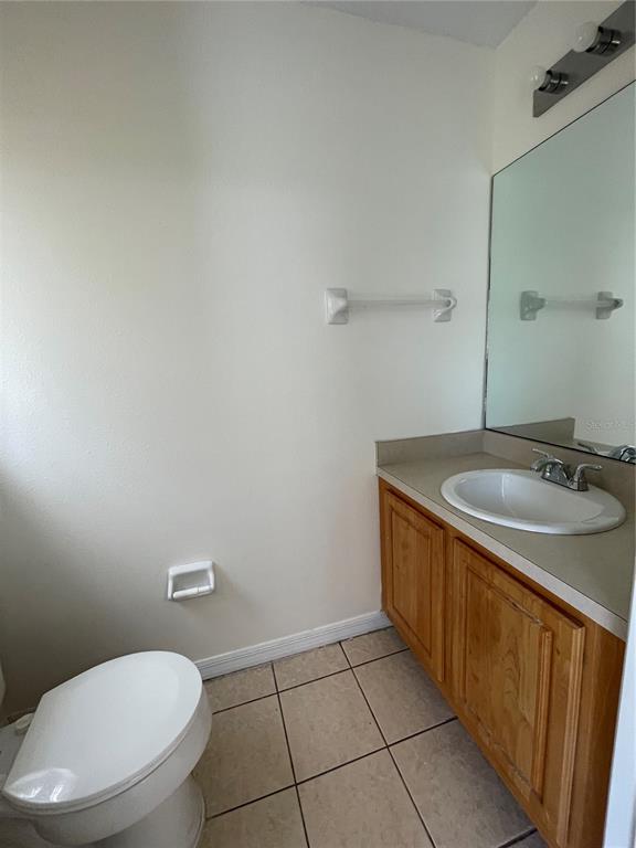 A bathroom features a white toilet, a wooden vanity with a sink, and a wall mirror — 342 CERVANTES DRIVE, KISSIMMEE, FL