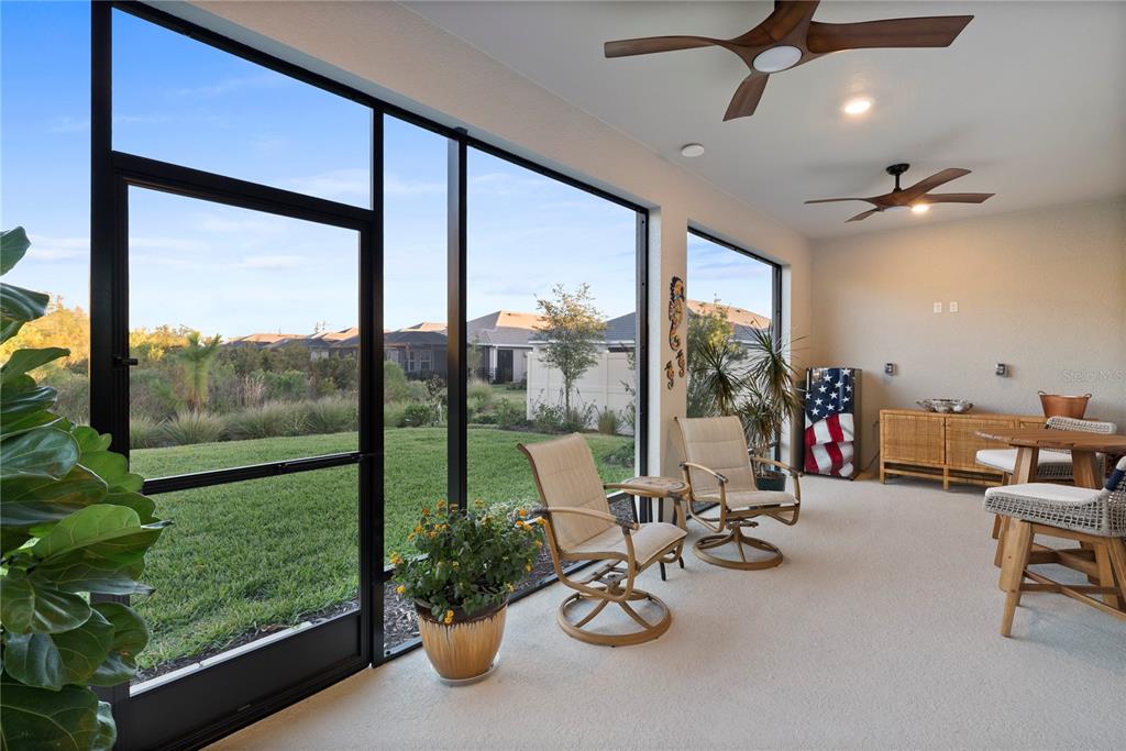 A screened-in patio features two ceiling fans, outdoor furniture, and a view of a grassy yard — 4618 ISONZO WAY, WESLEY CHAPEL, FL