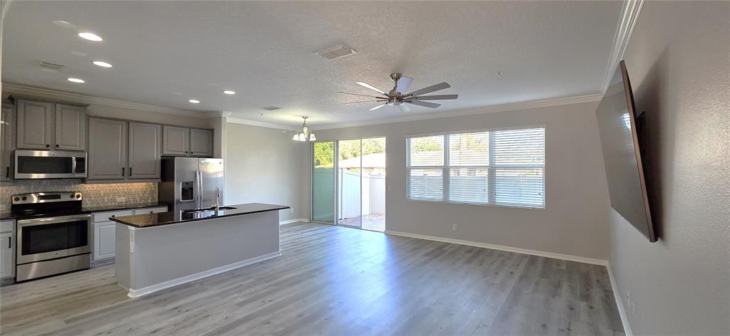A kitchen with gray cabinets and a breakfast island opens into a spacious living area — 760 WALKERS GROVE LANE, WINTER GARDEN, FL