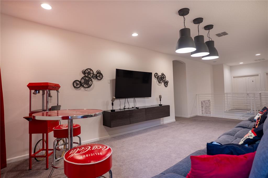An open-concept living room and kitchen featuring gray tufted sofas, tile flooring, and sliding doors — 2610 TRANQUILITY WAY, KISSIMMEE, FL