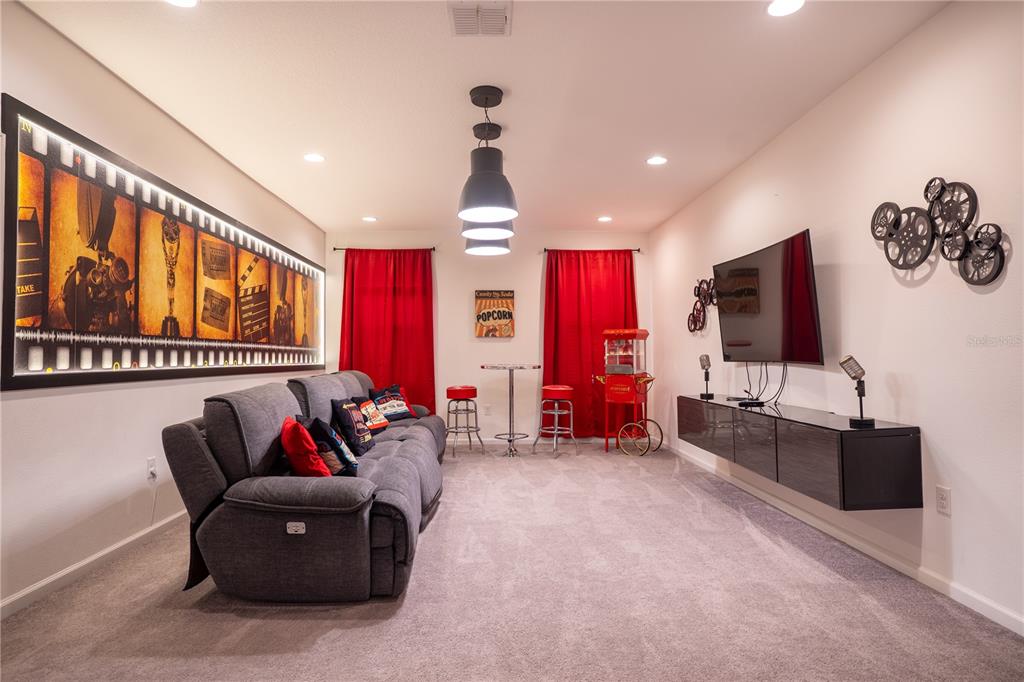 A living room features gray tufted sofas, a wall-mounted television, and sliding glass doors — 2610 TRANQUILITY WAY, KISSIMMEE, FL