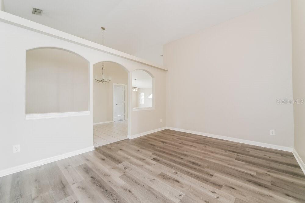 An empty room with light wood-look flooring, vaulted ceilings, and arched wall openings — 747 CITRUS COVE DRIVE, WINTER GARDEN, FL