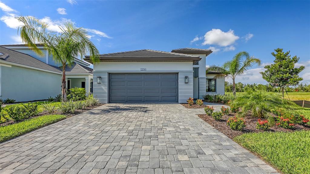 A single-story house with a gray garage door and a paved driveway under a blue sky — 2234 LADY PALM LOOP, BRADENTON, FL