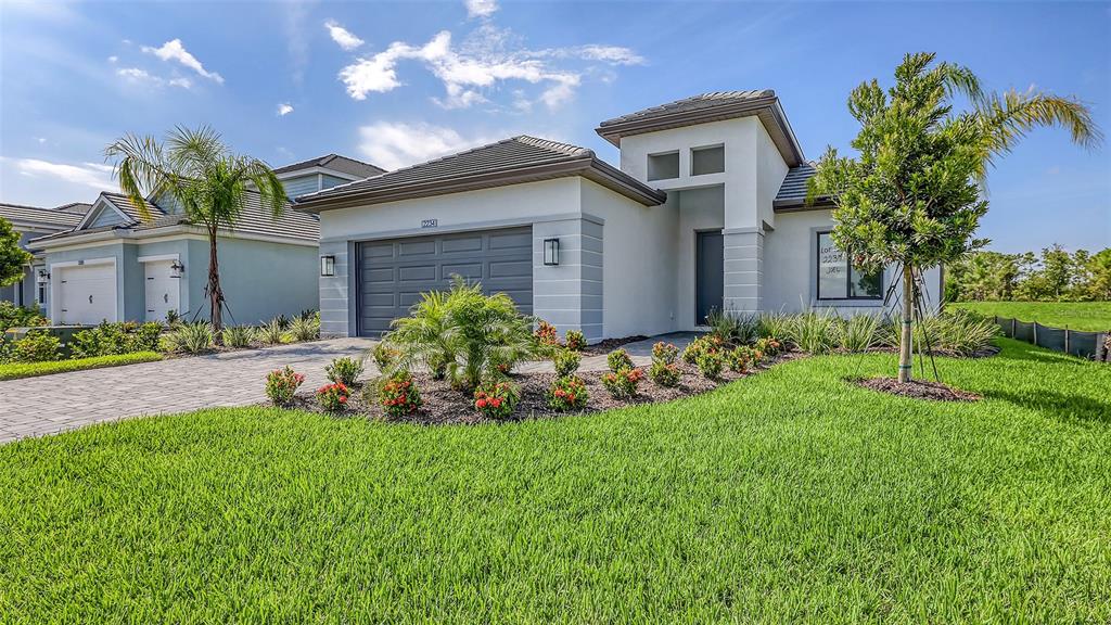 A single-story house with a gray garage, white stucco walls, and a landscaped front yard — 2234 LADY PALM LOOP, BRADENTON, FL