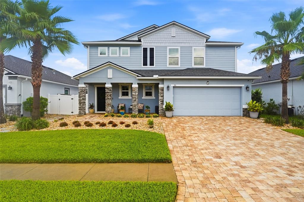 A two-story house with light blue siding, a stone-accented porch, and a paved driveway — 191 SANDSTONE DRIVE, ST AUGUSTINE, FL