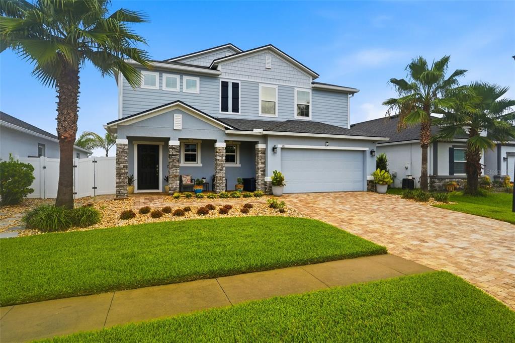 A two-story blue house with a stone-accented porch, a two-car garage, and palm trees — 191 SANDSTONE DRIVE, ST AUGUSTINE, FL