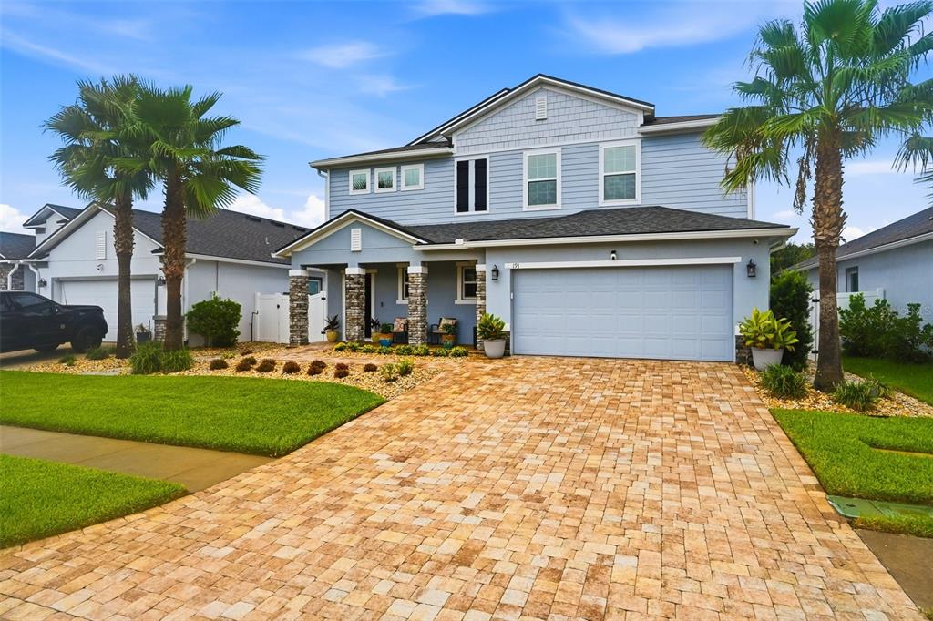 A two-story blue house with a stone-accented porch and a paved driveway — 191 SANDSTONE DRIVE, ST AUGUSTINE, FL