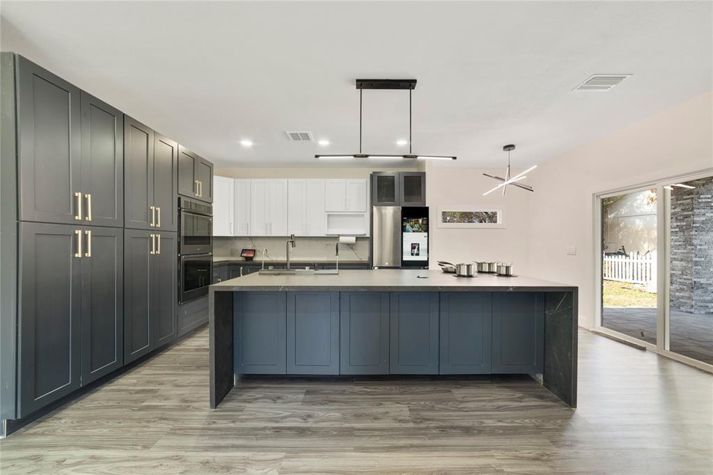 A modern kitchen features dark gray cabinetry, a large waterfall island, and white upper cabinets — 1013 RANDALL STREET, ORLANDO, FL