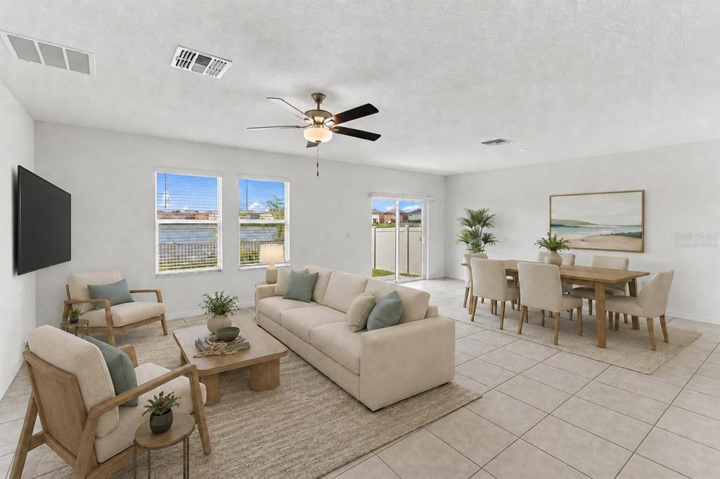 A bright, open-concept living and dining area features tile flooring, a ceiling fan, and neutral furniture — 5375 BLUE HORIZON WAY, WIMAUMA, FL