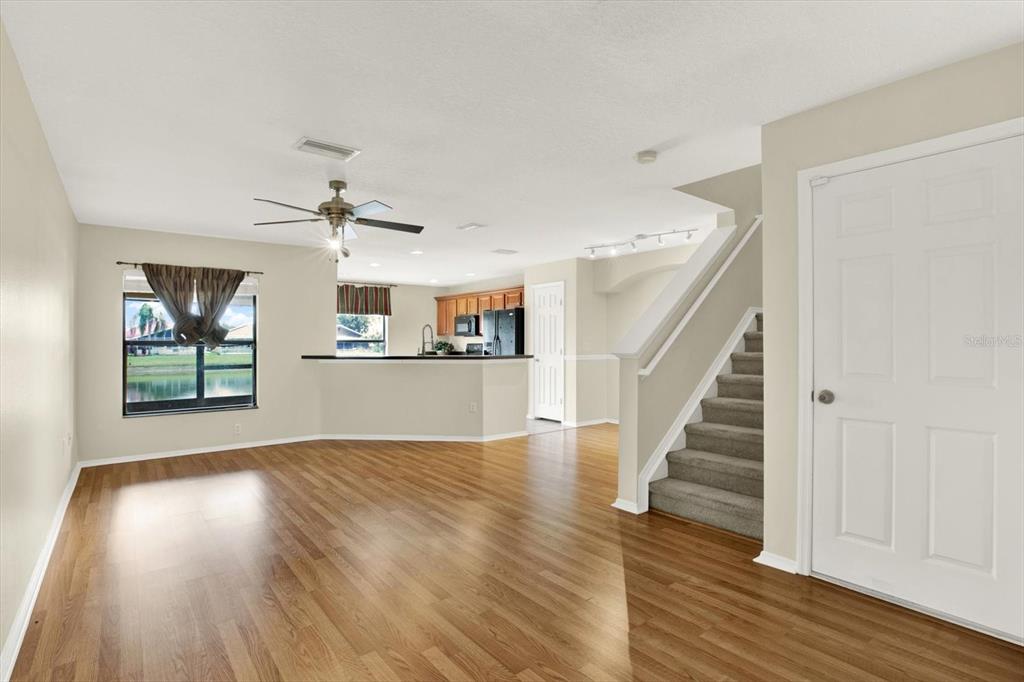 An open-concept living area features wood-look flooring, a kitchen with a breakfast bar, and stairs — 2630 EDGEWATER FALLS DRIVE UNIT 0, BRANDON, FL