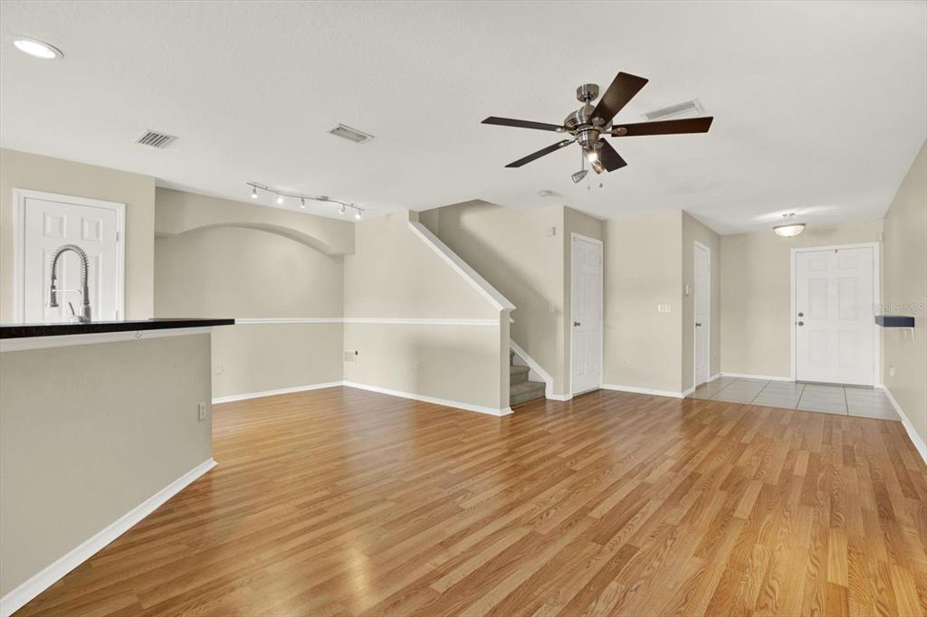 An open-concept living area features hardwood floors, a ceiling fan, and a staircase — 2630 EDGEWATER FALLS DRIVE UNIT 0, BRANDON, FL