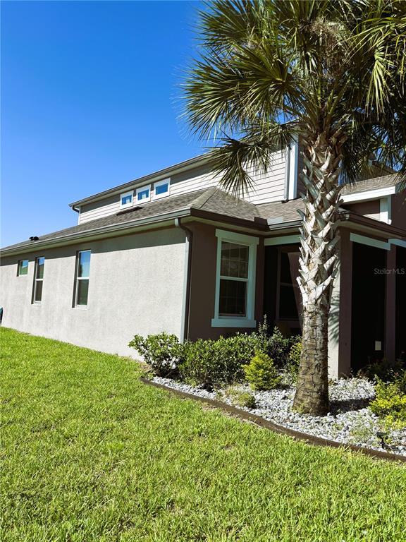 A side view of a two-story house with tan stucco walls and a palm tree — 796 GRAZIE LOOP, DAVENPORT, FL