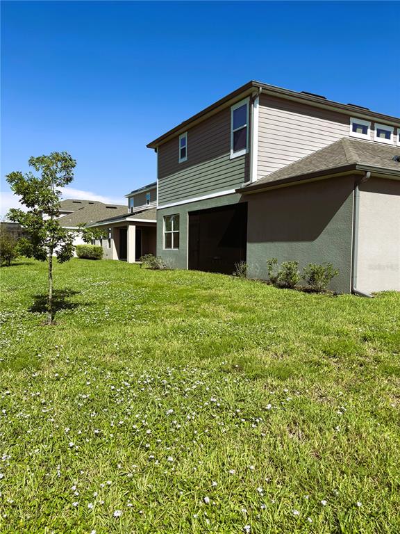 The exterior side and rear view of a two-story suburban house with a grassy lawn — 796 GRAZIE LOOP, DAVENPORT, FL