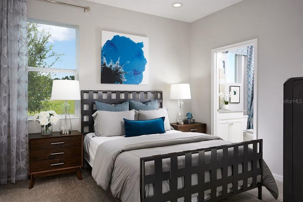 A bedroom features a dark grid-patterned bed frame, gray bedding, and a blue accent pillow — 796 GRAZIE LOOP, DAVENPORT, FL