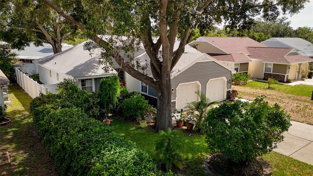 A gray-sided house with a two-car garage and a large tree in the front yard — 3174 PHLOX DRIVE, PALM HARBOR, FL