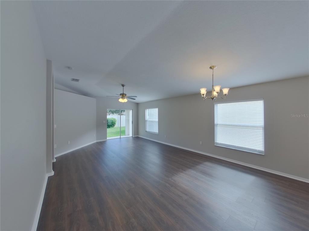 An open-concept living area features dark wood-look flooring, light gray walls, and a chandelier — 15512 TELFORD SPRING DRIVE, RUSKIN, FL