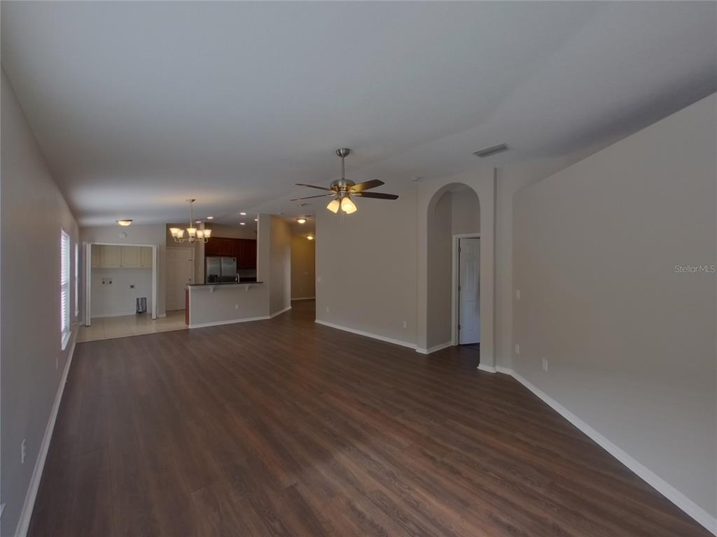 An open-concept living area features dark wood-look flooring, neutral walls, and a ceiling fan — 15512 TELFORD SPRING DRIVE, RUSKIN, FL