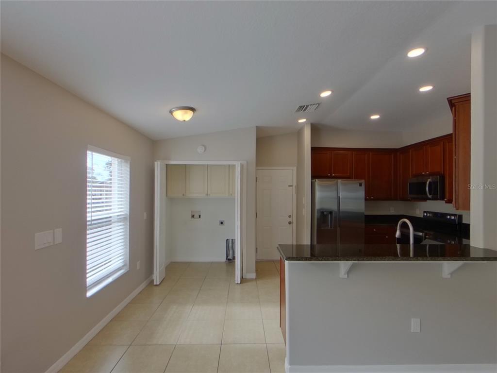 A kitchen with dark wood cabinets and a breakfast bar opens to a laundry area — 15512 TELFORD SPRING DRIVE, RUSKIN, FL