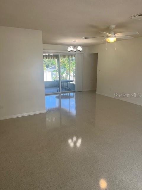 An open living area features polished terrazzo flooring, a ceiling fan, and sliding glass doors — 1630 PICARDY CIRCLE, CLEARWATER, FL