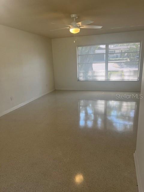 An empty room features light-colored walls, a ceiling fan, and polished terrazzo flooring — 1630 PICARDY CIRCLE, CLEARWATER, FL
