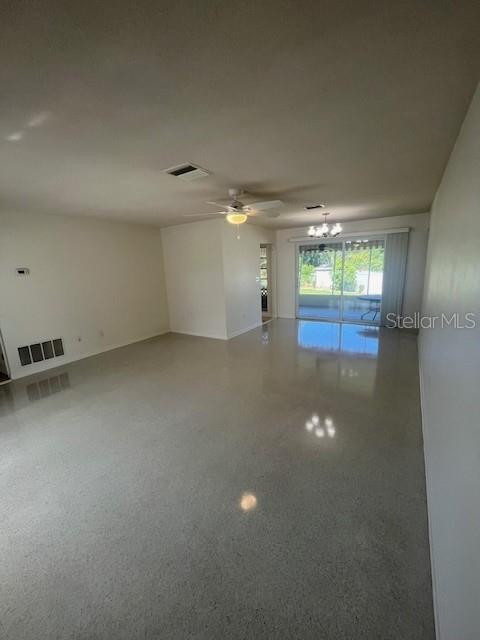 A spacious living room features polished terrazzo floors, a ceiling fan, and sliding glass doors — 1630 PICARDY CIRCLE, CLEARWATER, FL