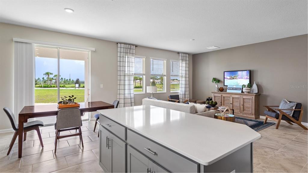 An open-concept living and dining area features a kitchen island, tile floors, and sliding doors — 1106 JAMES PAUL RD, DAVENPORT, FL
