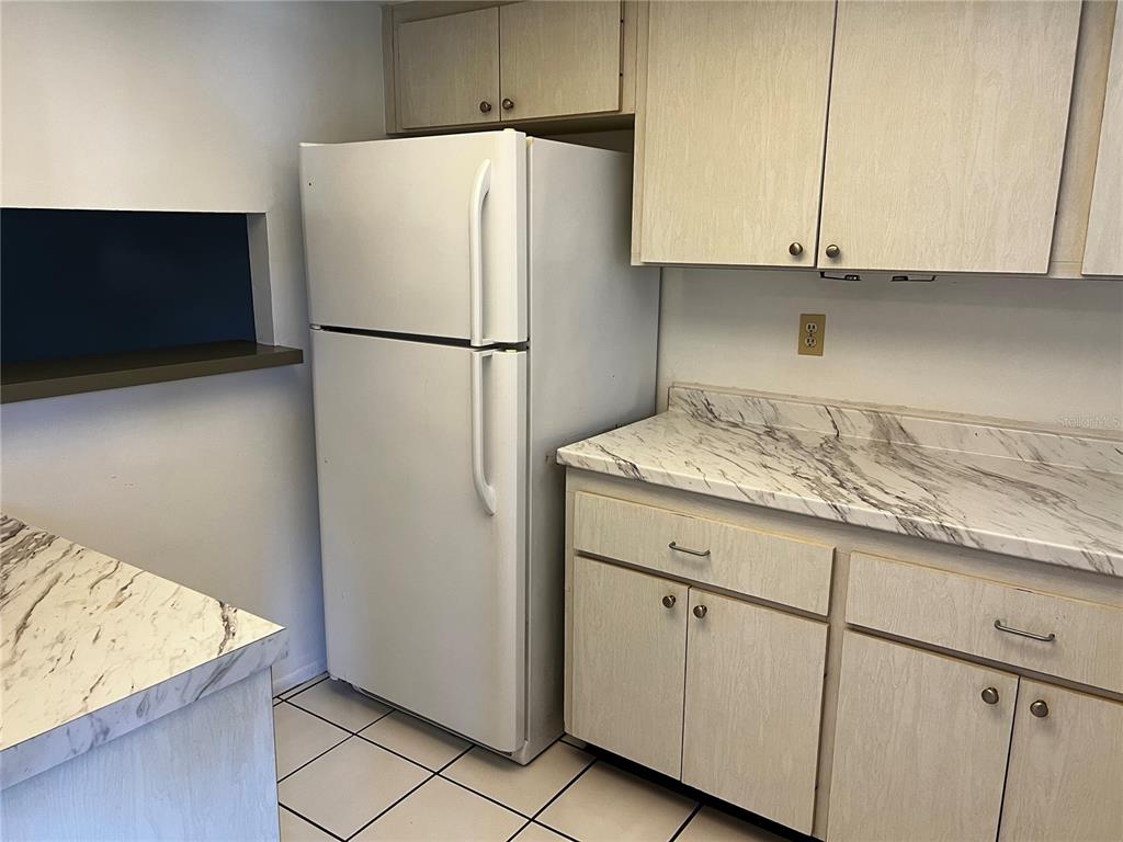 A kitchen features a white refrigerator, light wood cabinets, and marble-patterned laminate countertops — 4112 HERON WAY UNIT B106, BRADENTON, FL