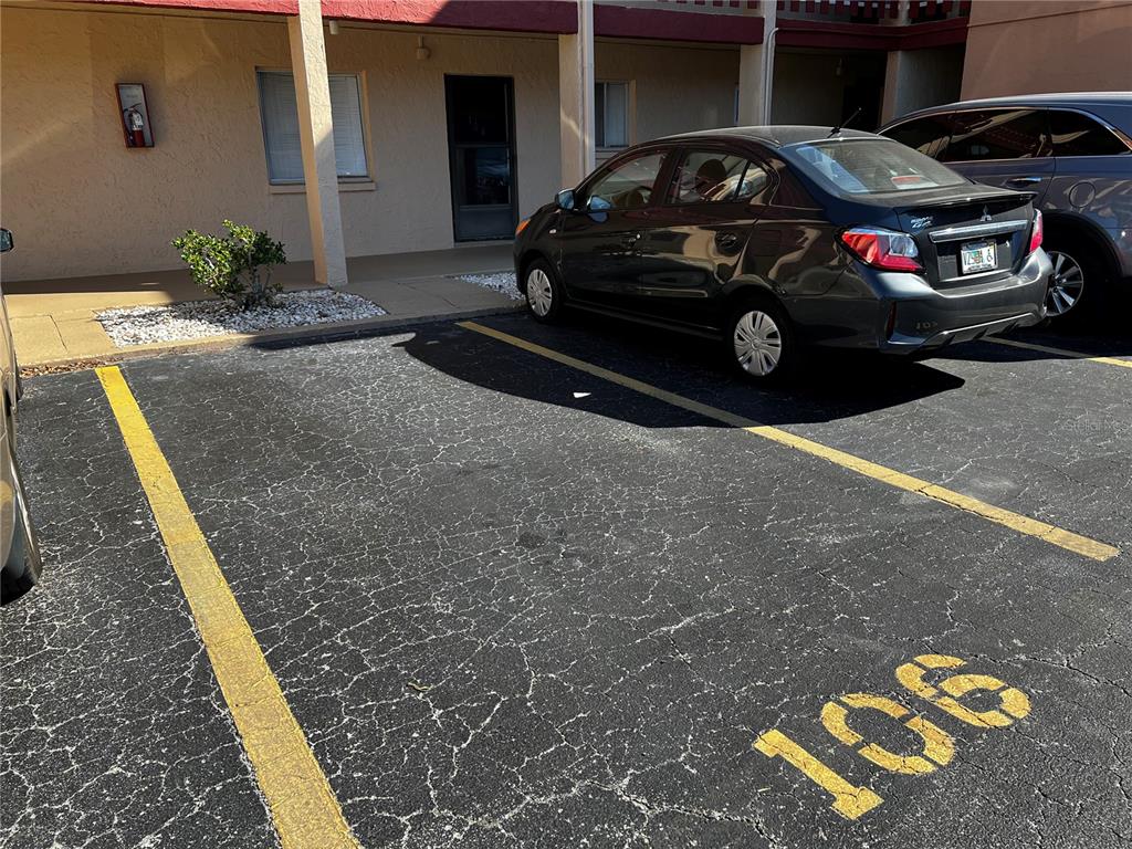 A parking space numbered 106 is located in front of a building with a parked car — 4112 HERON WAY UNIT B106, BRADENTON, FL